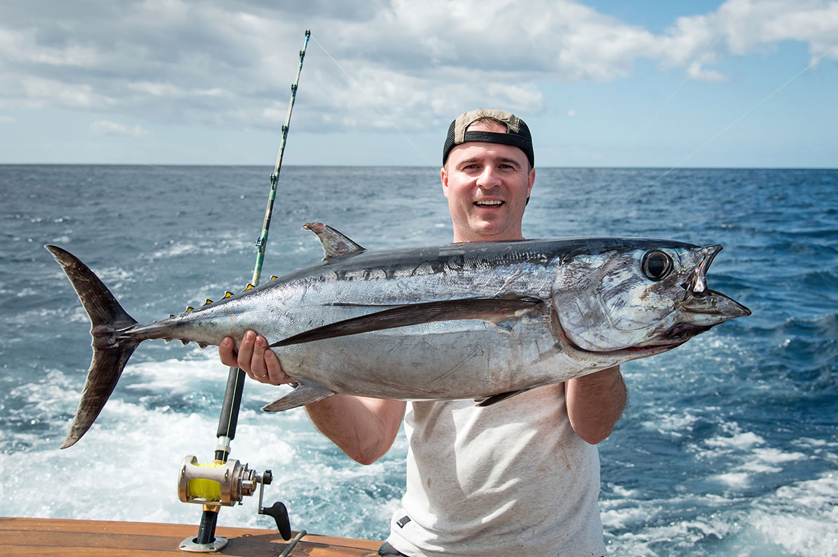 Experienced angler holding a large tuna caught during a deep-sea fishing trip