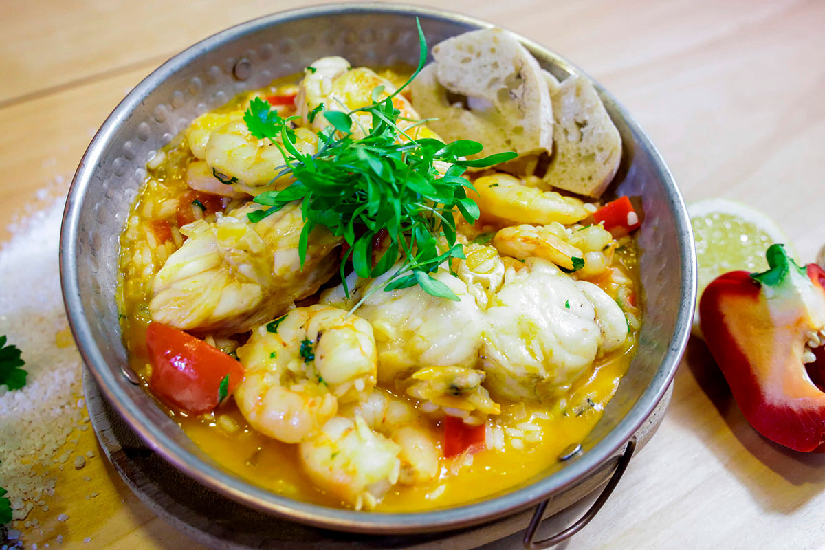 Creamy Arroz de Tamboril garnished with fresh herbs.