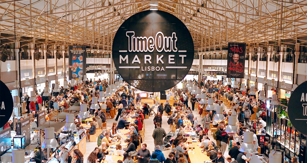 Crowds enjoying diverse food stalls inside Mercado da Ribeira.