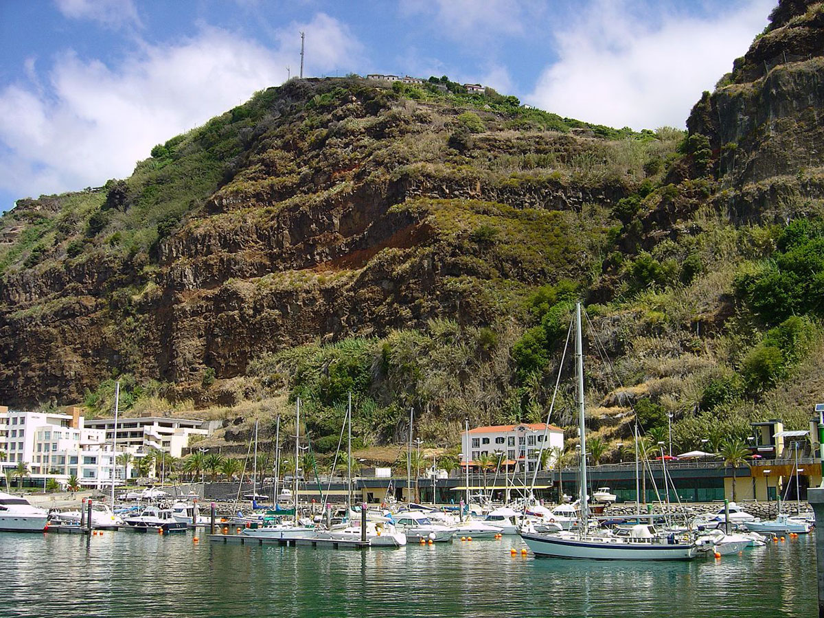 Boats moored at Calheta Marina with cliffs in the background