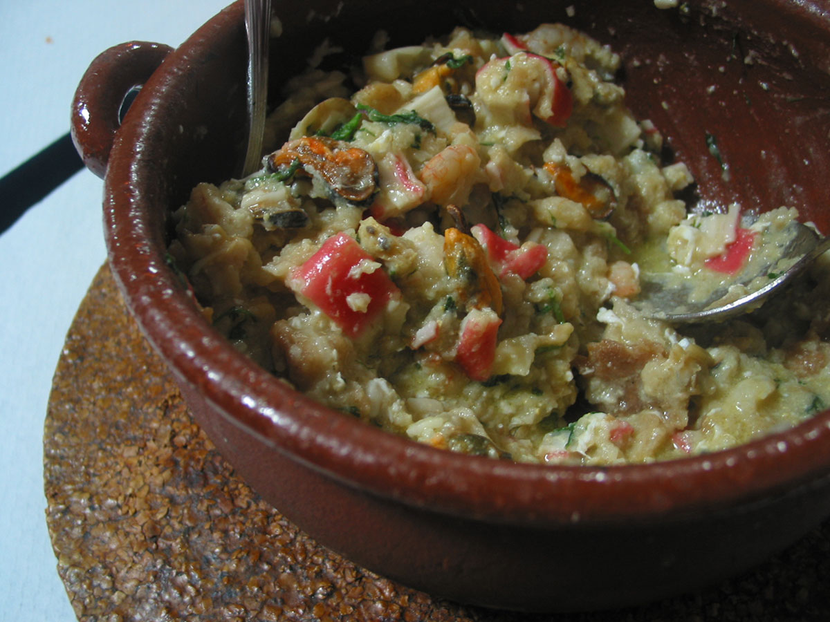 Traditional Portuguese Açorda de Marisco dish served at sunset, with vibrant seafood and rustic bread in a coastal Ria Formosa setting.