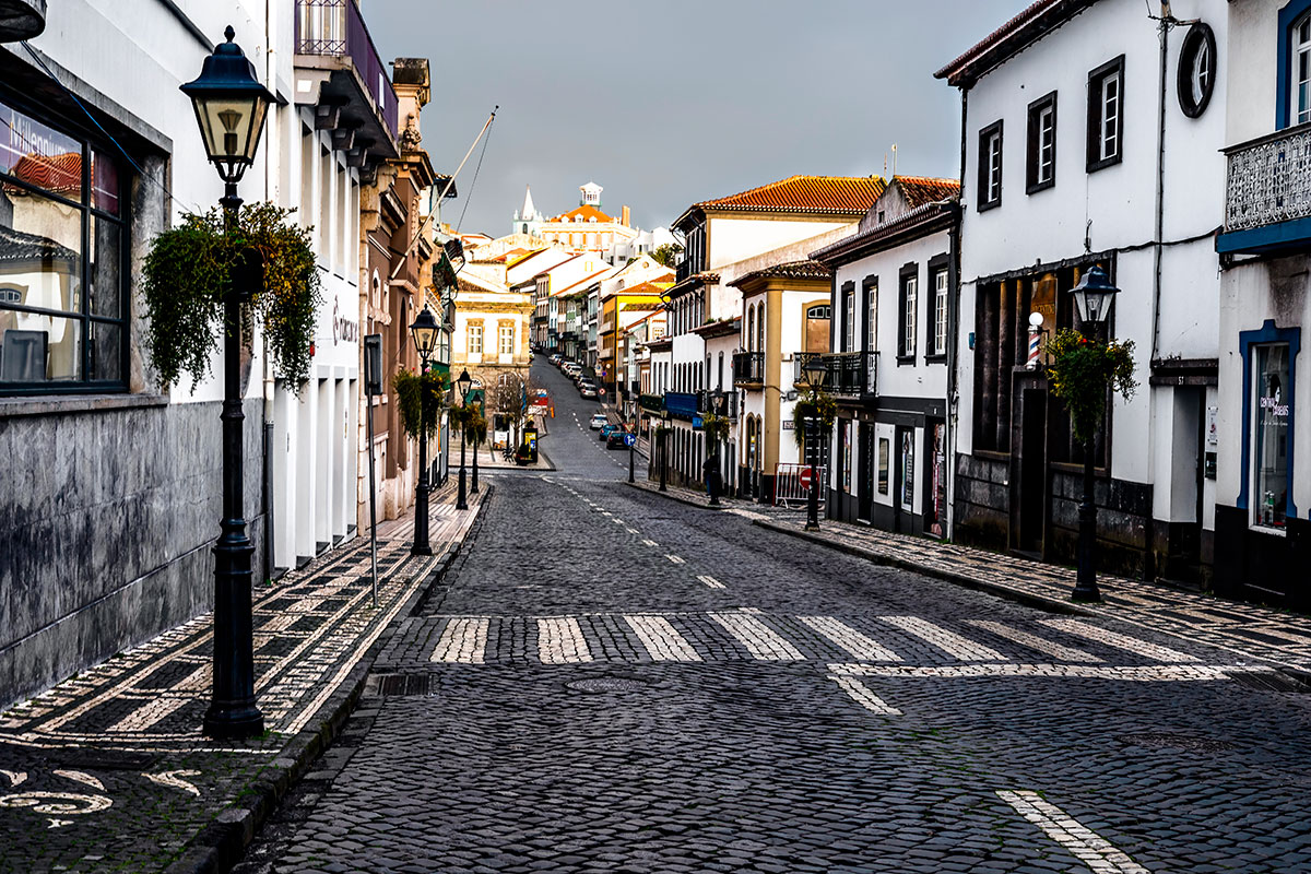 Cobbled street in Angra do Heroísmo with colorful colonial buildings.
