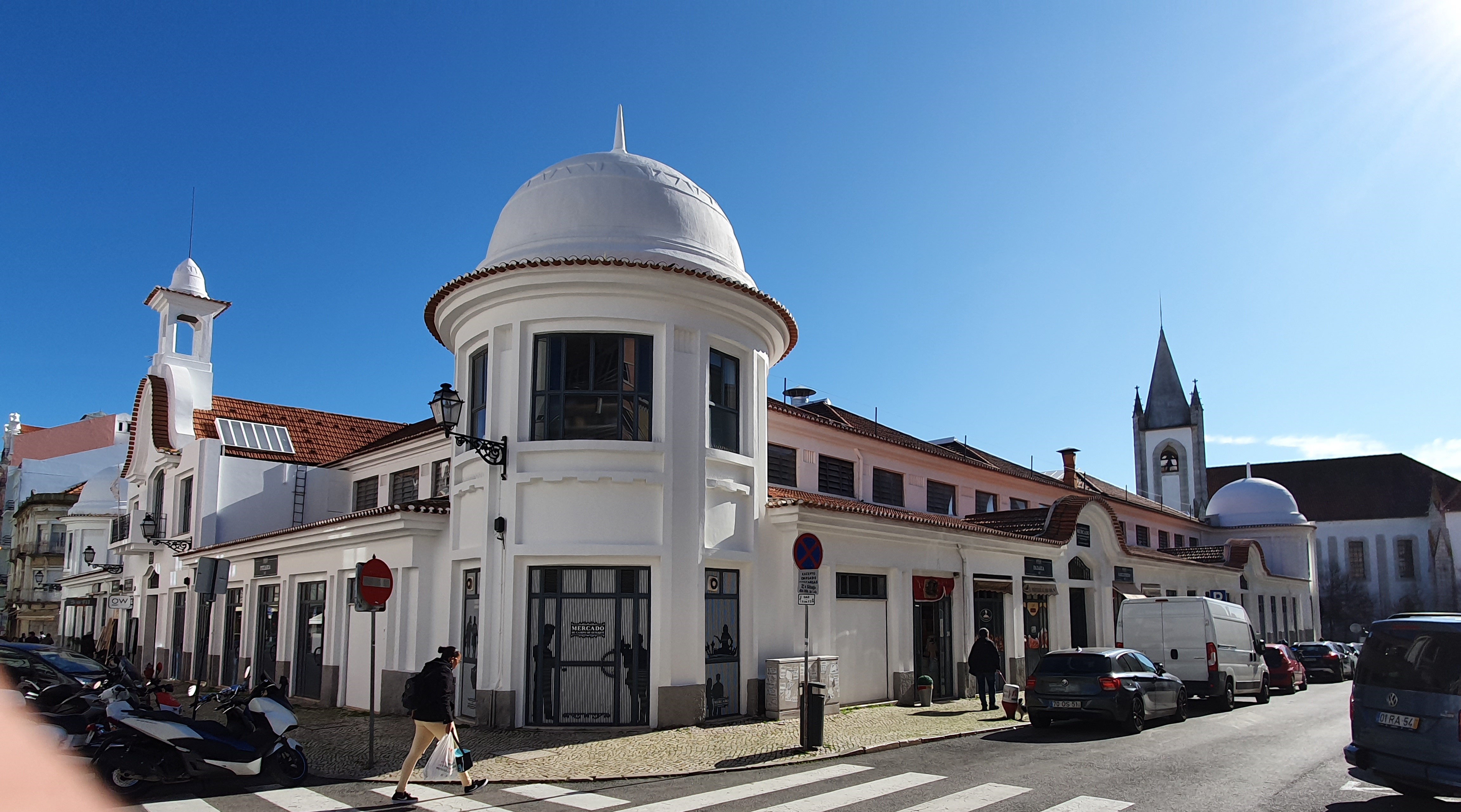 Exterior of Mercado de Campo de Ourique featuring its classic red-brick façade and arched entrances under a bright Lisbon sky.