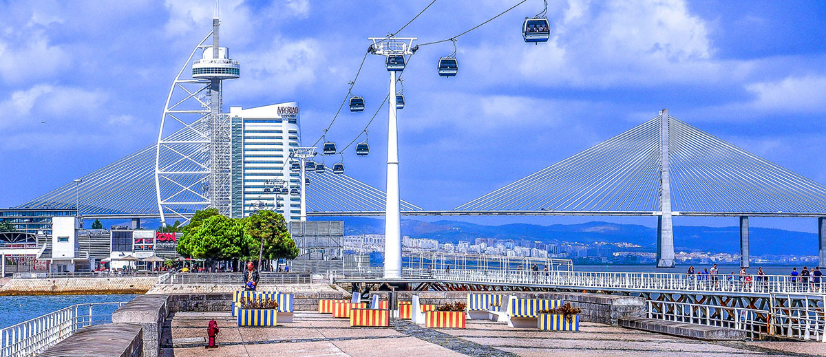 Modern riverside view of Parque das Nações with the Vasco da Gama Tower, cable cars, and boardwalk along the Tagus River.