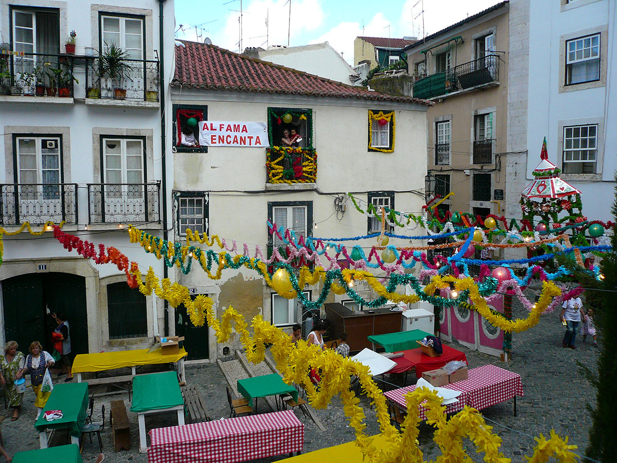 Colorful streets of Alfama decorated with streamers, paper lanterns, and sardine grills during the Santo António festivities in Lisbon.