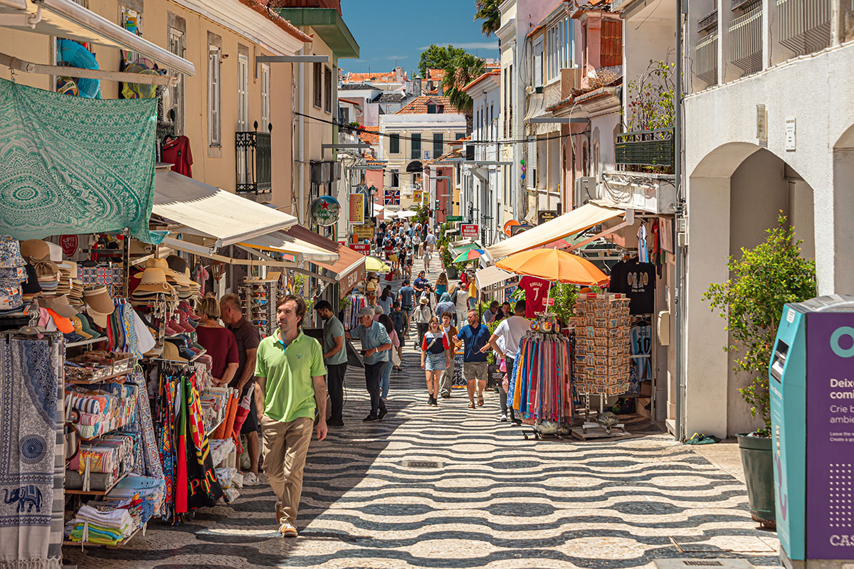 Narrow cobblestone street with pastel houses and local shops