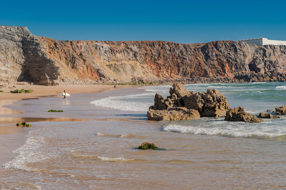Surfer going to riding a wave at Praia do Tonel, Sagres