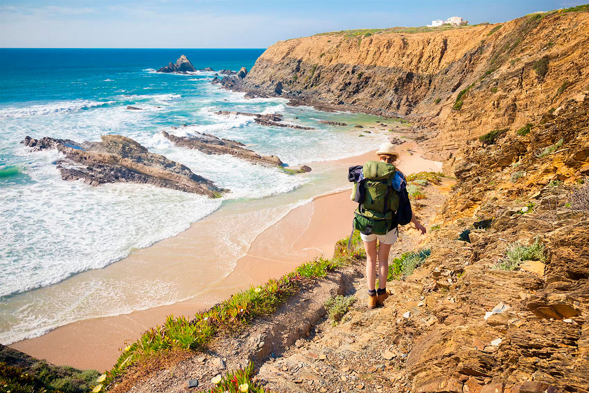 Hiker overlooking ocean cliffs along the Rota Vicentina in Sagres
