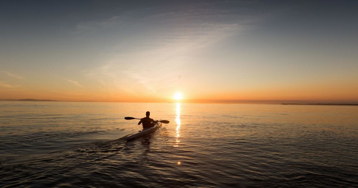 Kayaker exploring sea caves near Sagres coastline