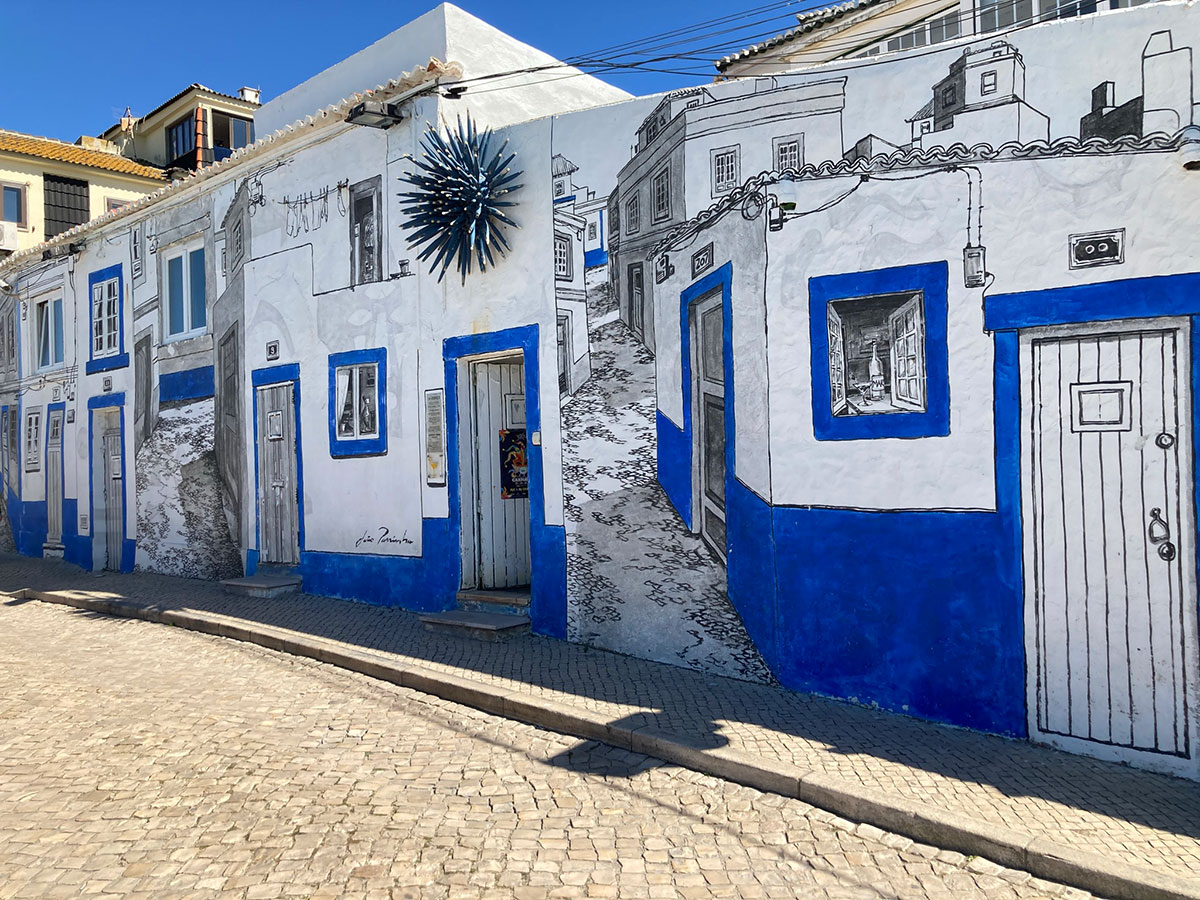 Colorful street art mural in Ericeira depicting ocean waves and local culture