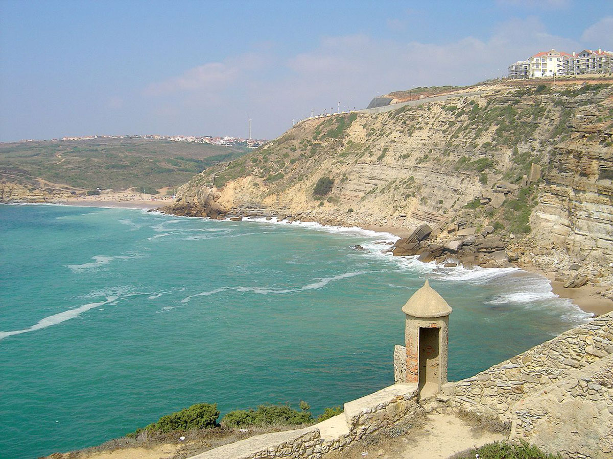 Secluded Praia da Orelheira beach with golden sands and surrounding cliffs in Ericeira