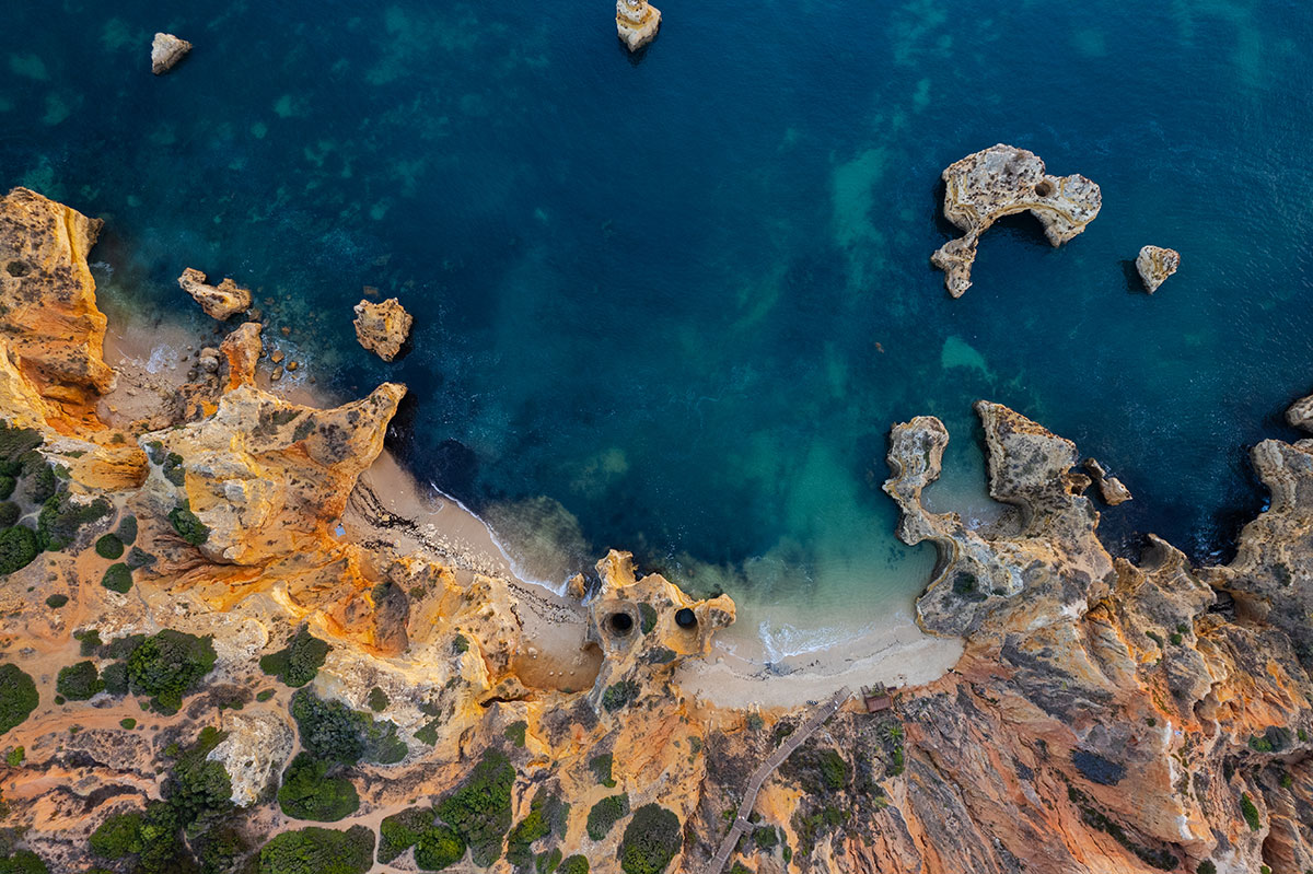 View of Praia do Camilo beach with wooden staircase and turquoise waters
