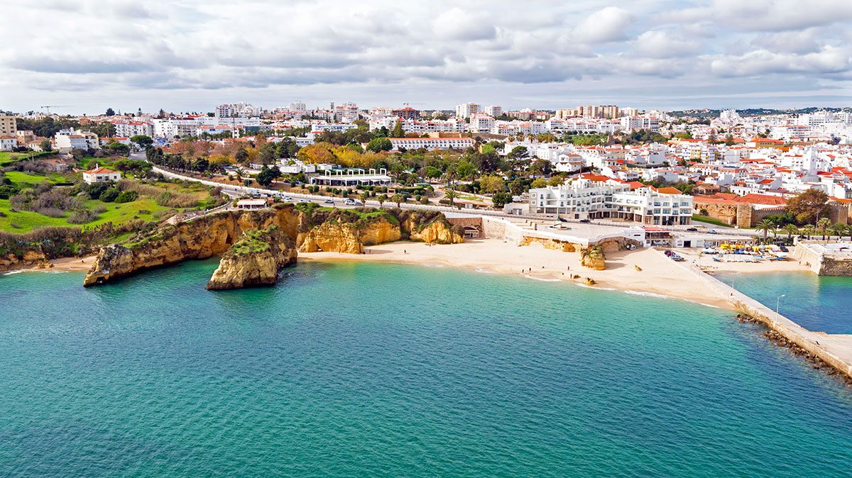 Aerial view of Lagos, Algarve showing the historic old town, marina, and golden coastline with cliffs and beaches.