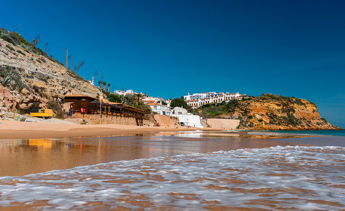 Golden sands of Burgau Beach bordered by rugged cliffs