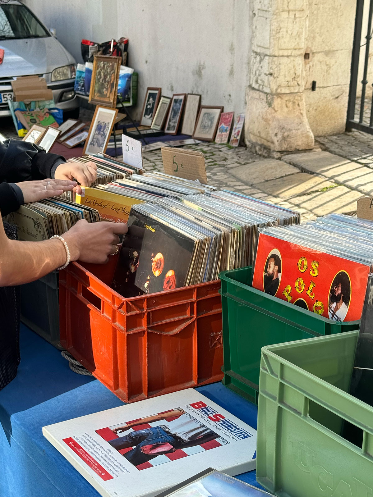 Street market in Burgau displaying vintage vinyl records and framed photographs on a sunny day.