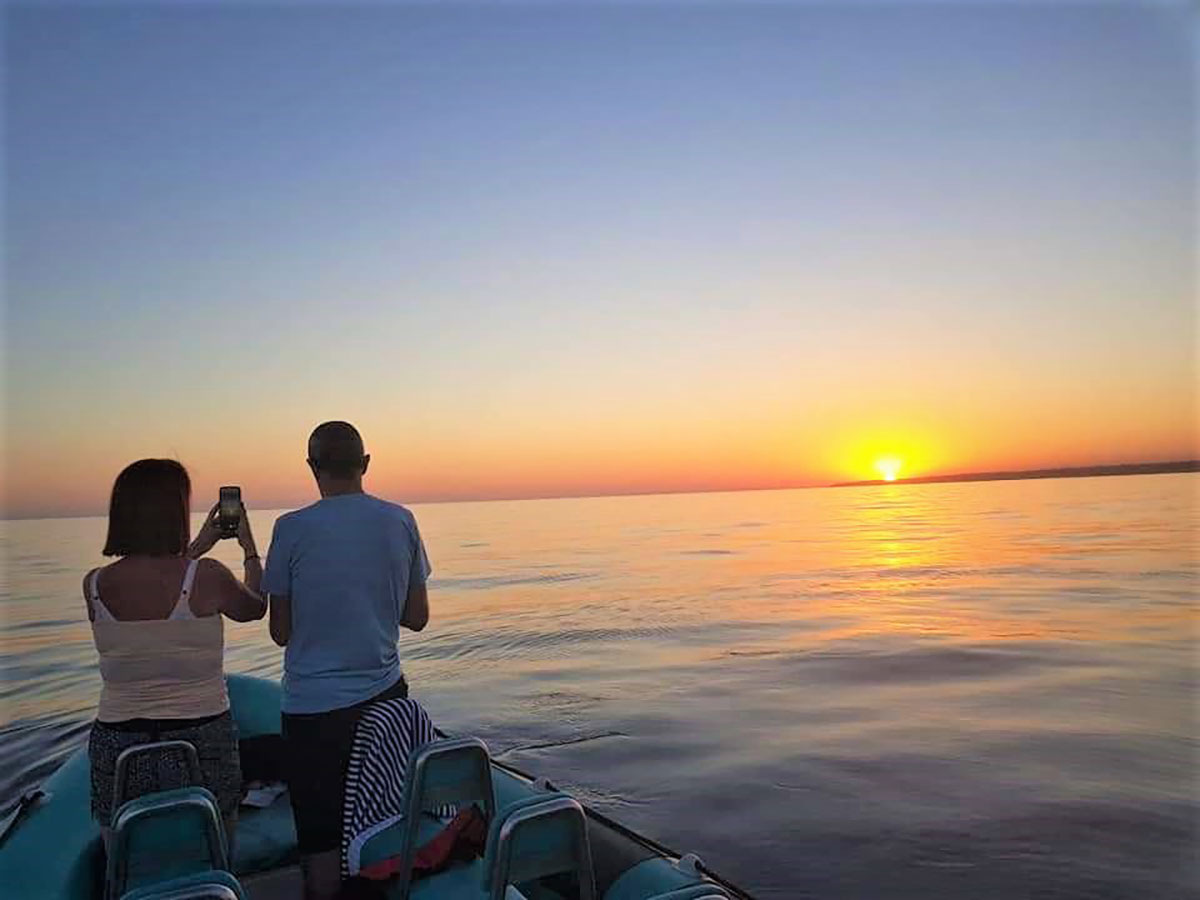 Couple enjoying a sunset sail with sunset in the background