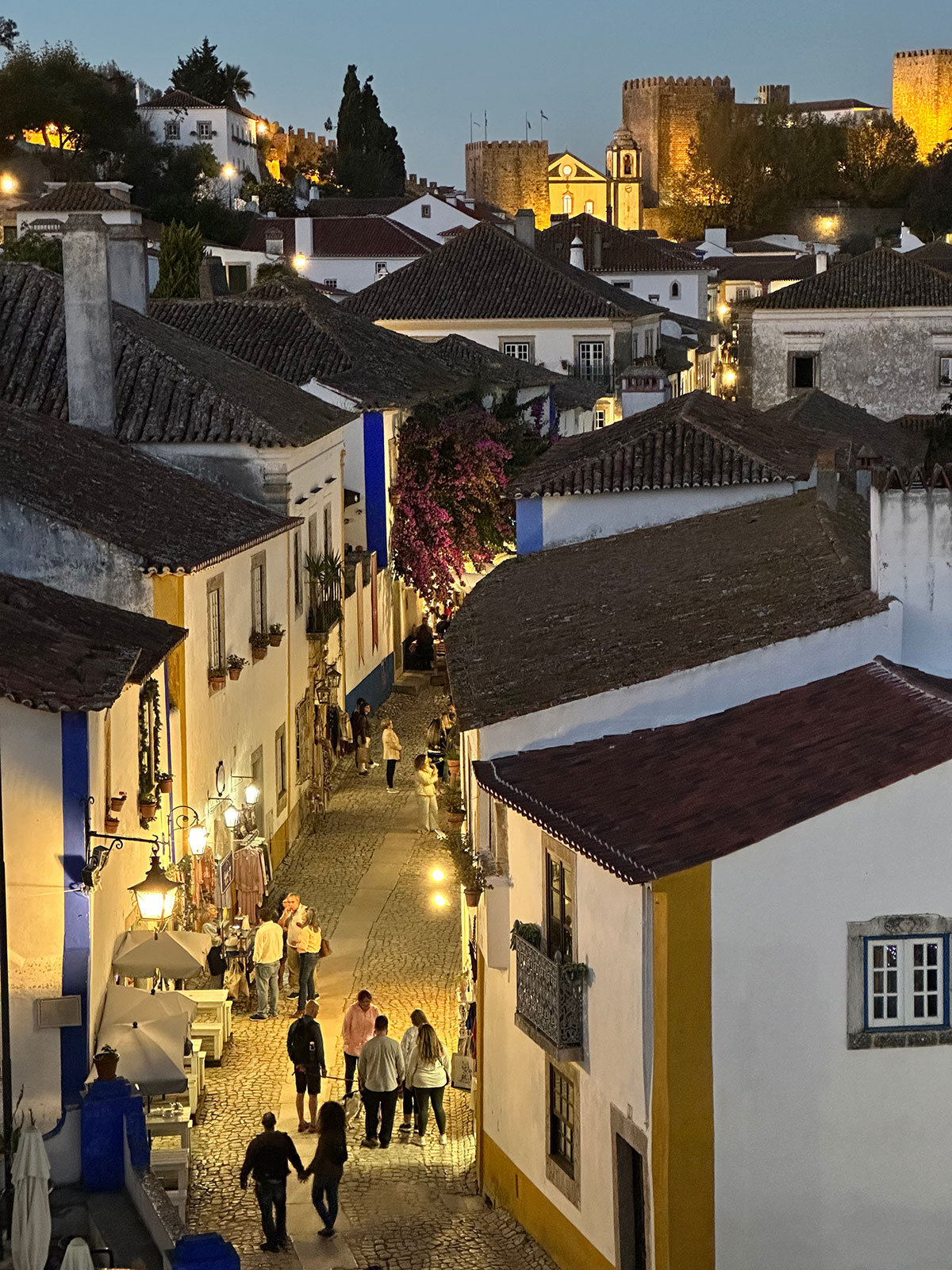 The bustling Rua Direita in Óbidos, lined with shops, cafes, and traditional houses.