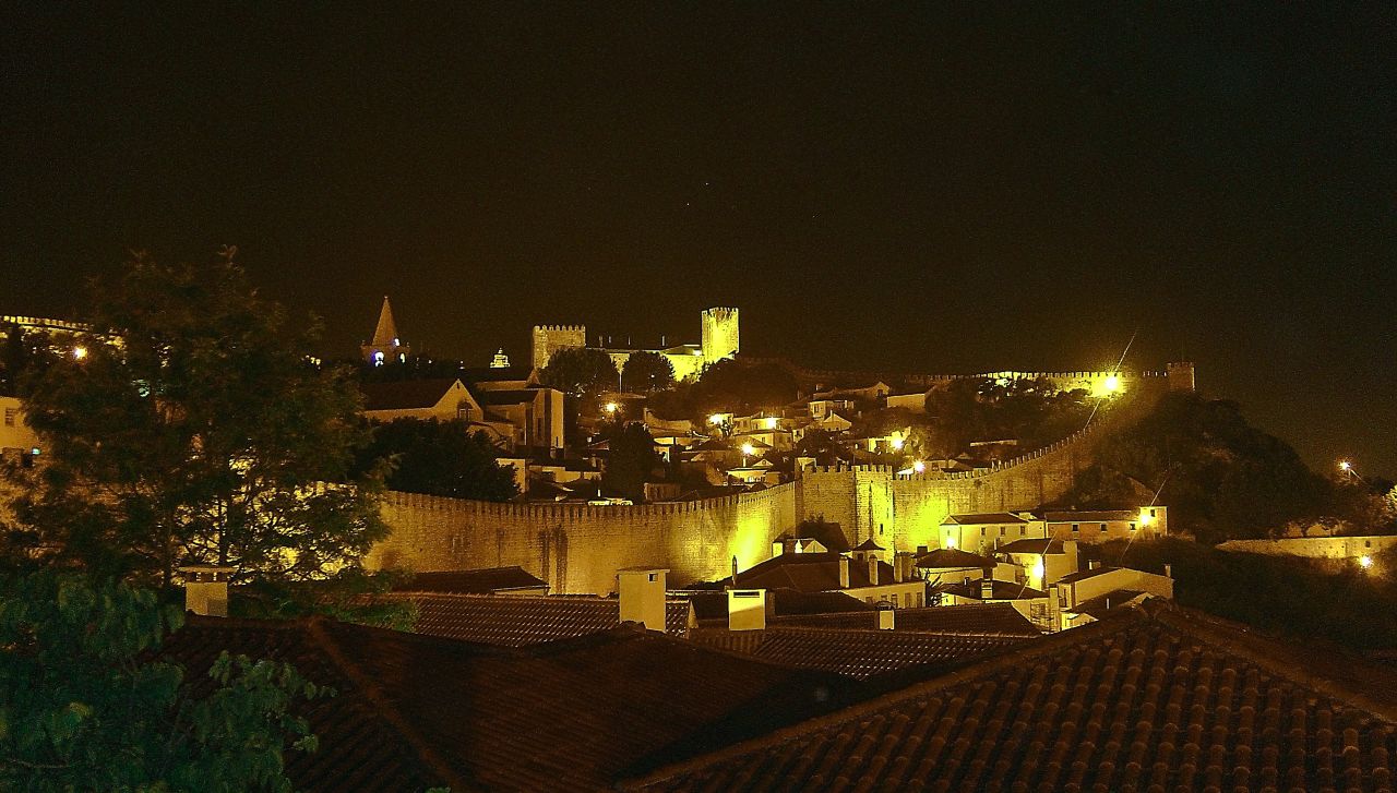Nighttime view of Óbidos, with illuminated streets and historic buildings.