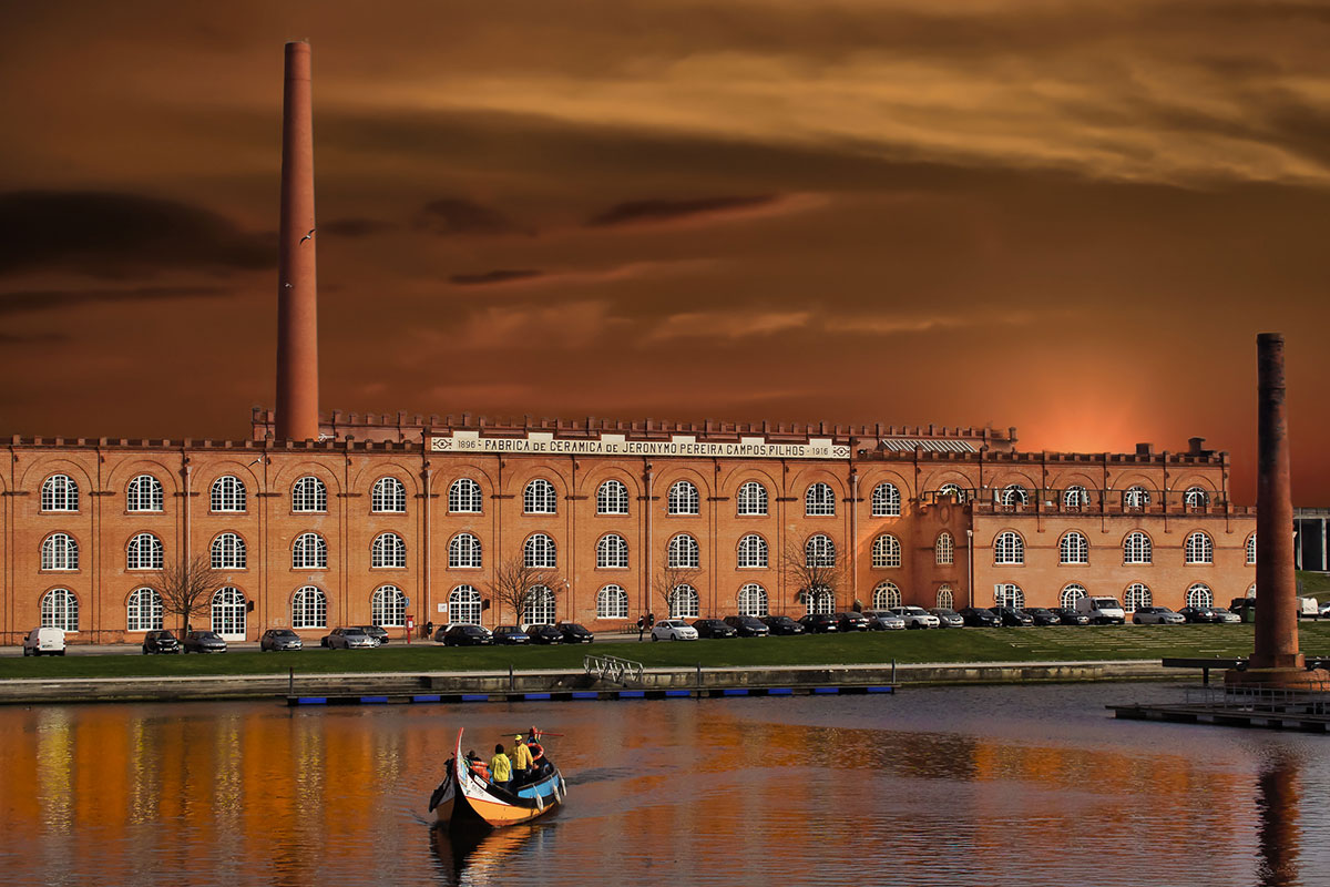 Historic red-brick building of Fábrica de Cerâmica de Jerónymo Pereira Campos, Filhos reflected on the canal waterfront in Aveiro.