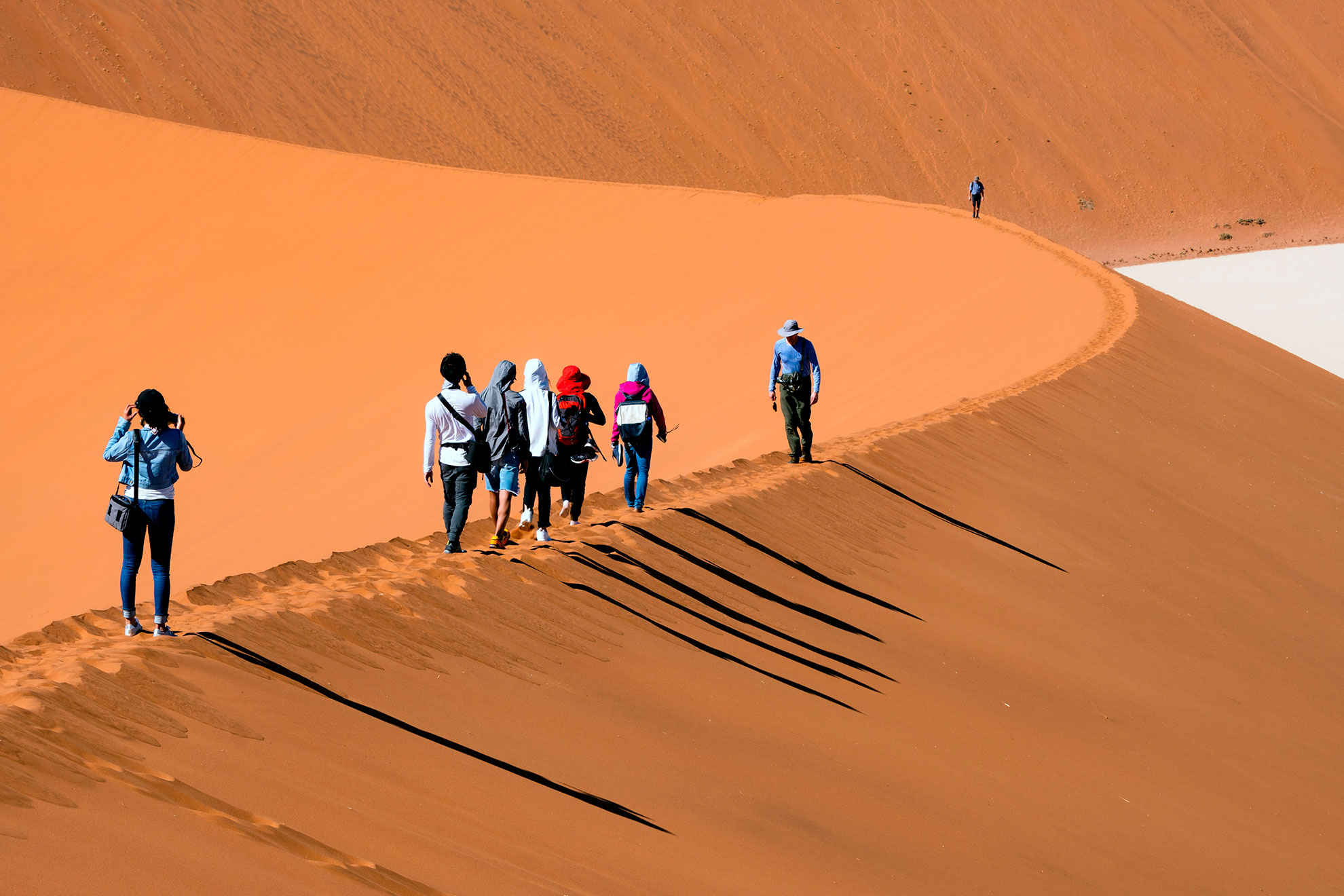 Travelers walking on the sand dune desert with clear blue sky background