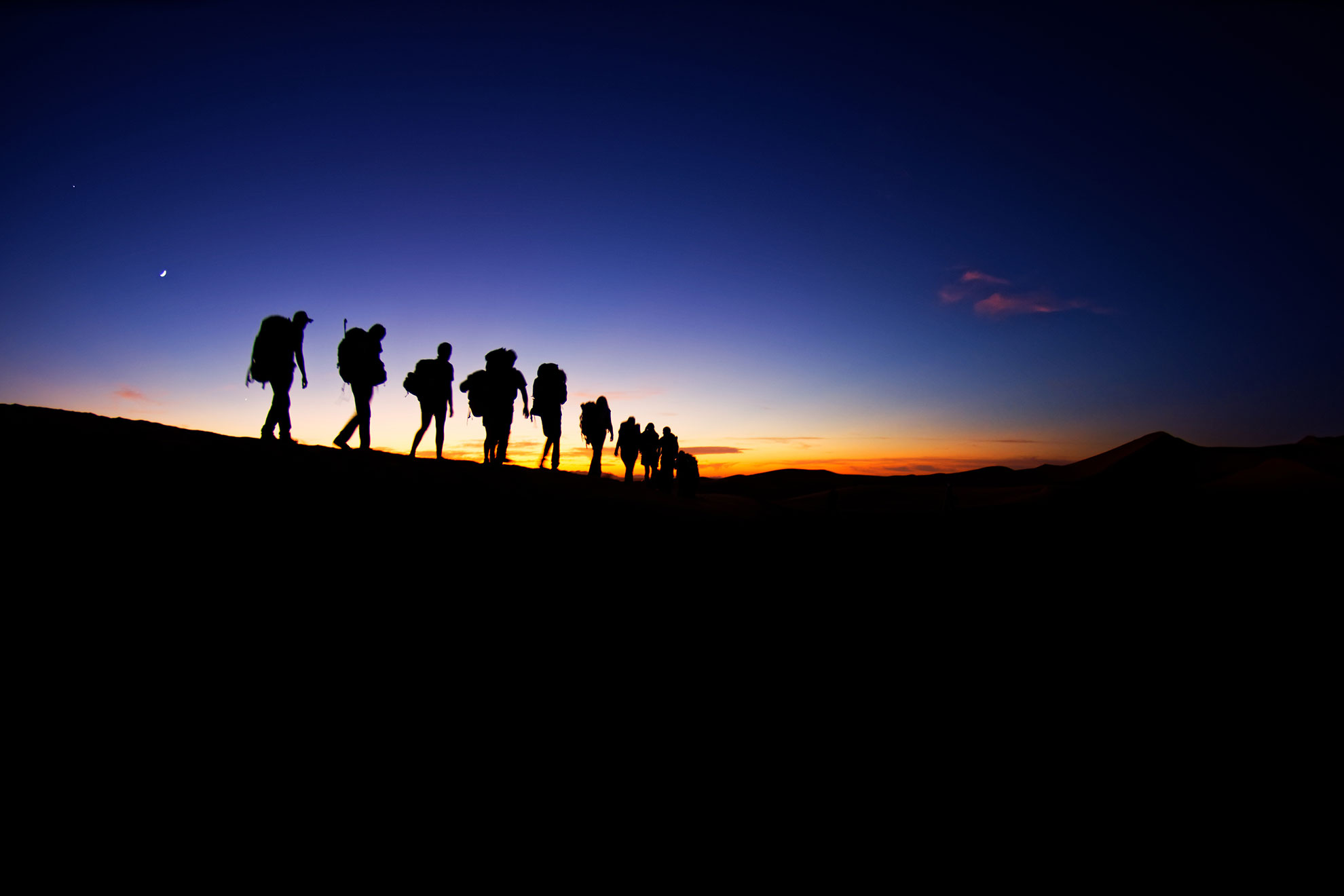 Desert landscape near Merzouga, small village in Morocco, known for its proximity to Erg Chebbi, tourists visiting Morocco, group of turists walking on the dune during sunrise