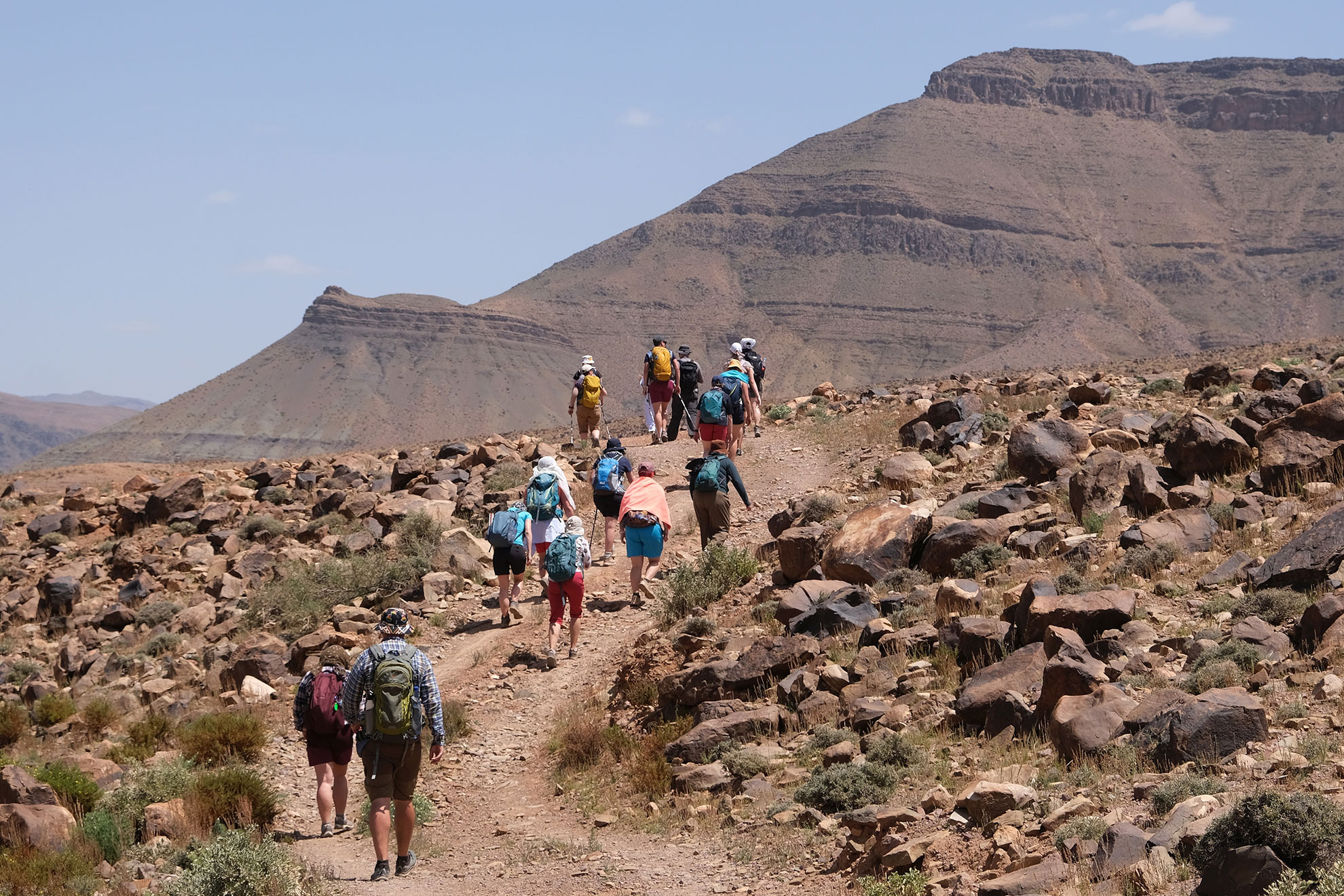 Amazing mountain landscapes of Jebel Saghro with volcanic rocks eroded by wind and time and group of trekking tourists. Atlas, Anti Atlas, Morocco