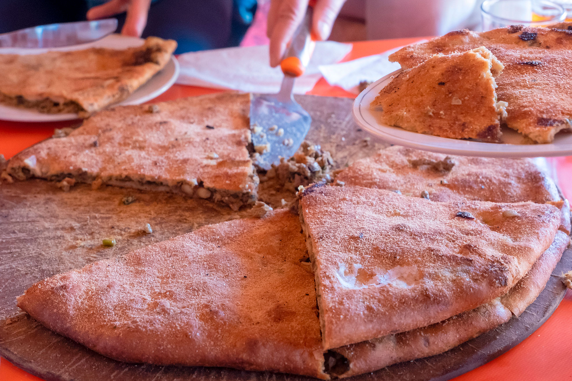 Medfouna, Berber pizza cut into slices, traditional and rustic culinary dish originally from the Morocco. Taken in Rissani Sahara desert, blurred background