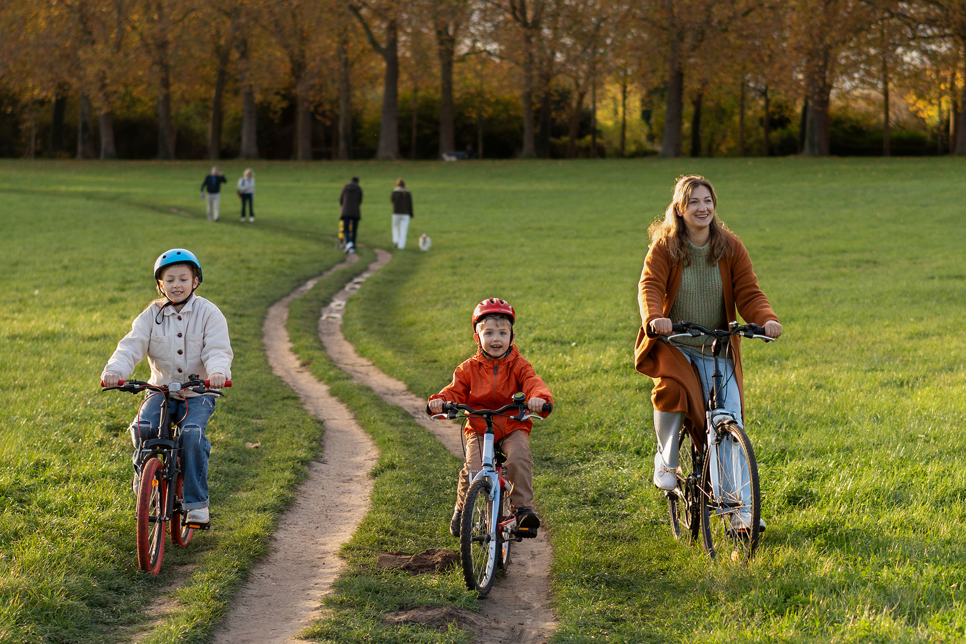 Happy family cycling together on sunny autumn park grass trail in Pond of the Swiss (Piece d'Eau des Suisses) Versailles