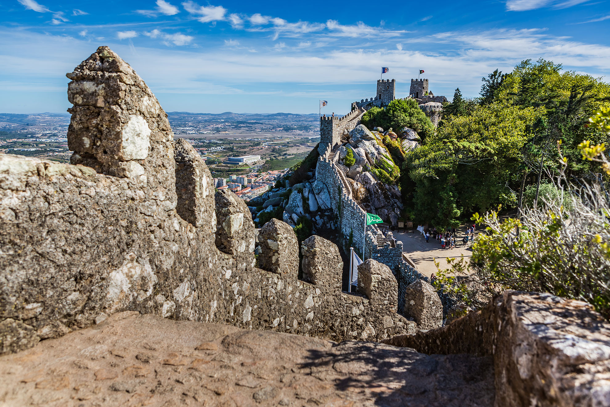 Ancient battlements of the Moorish Castle winding across rocky hilltop in Sintra, Portugal, with panoramic views over the Lisbon coast