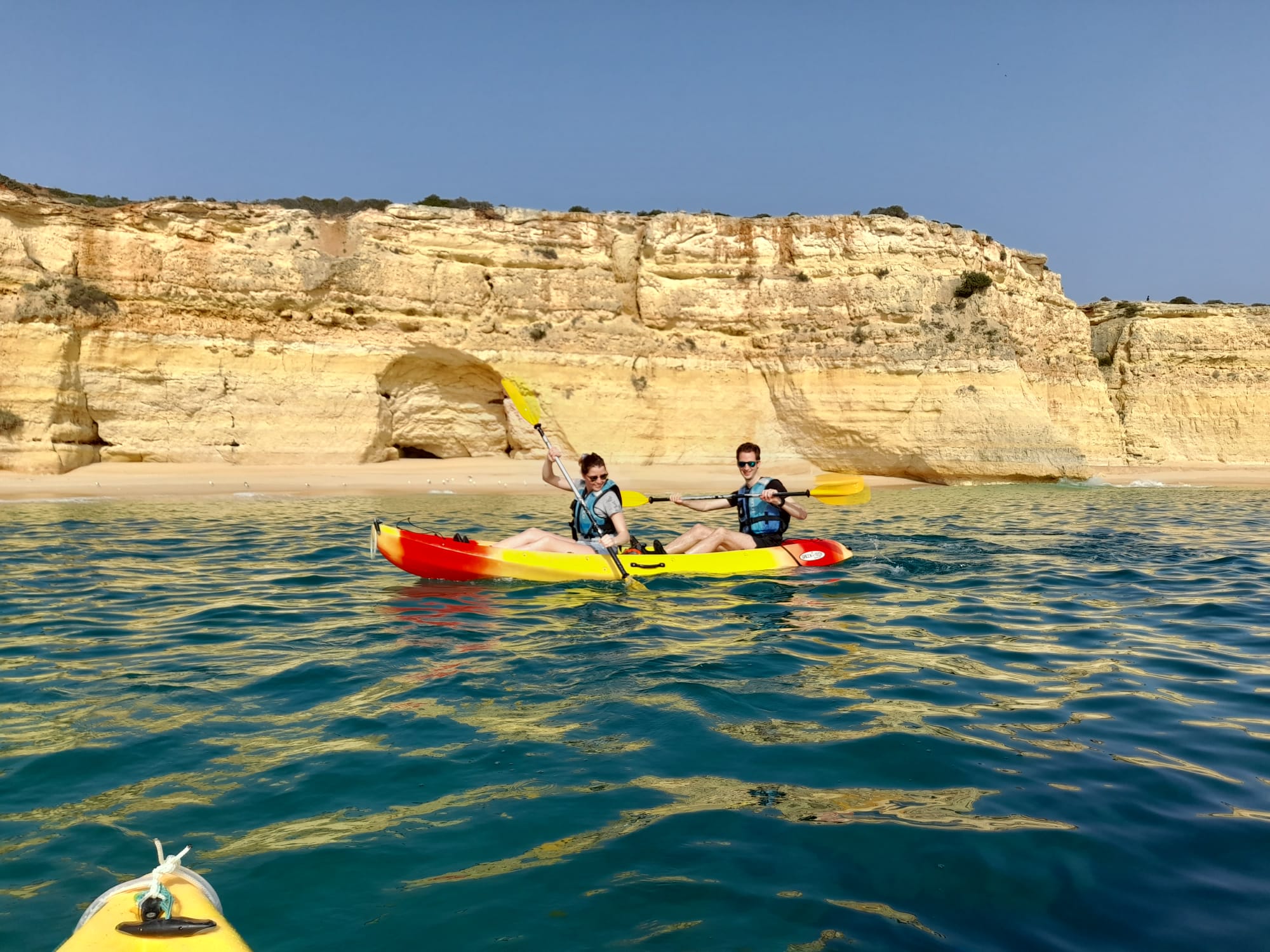 Kayak tour guide leading a small group inside Benagil Cave, Algarve, golden sandstone walls and turquoise water