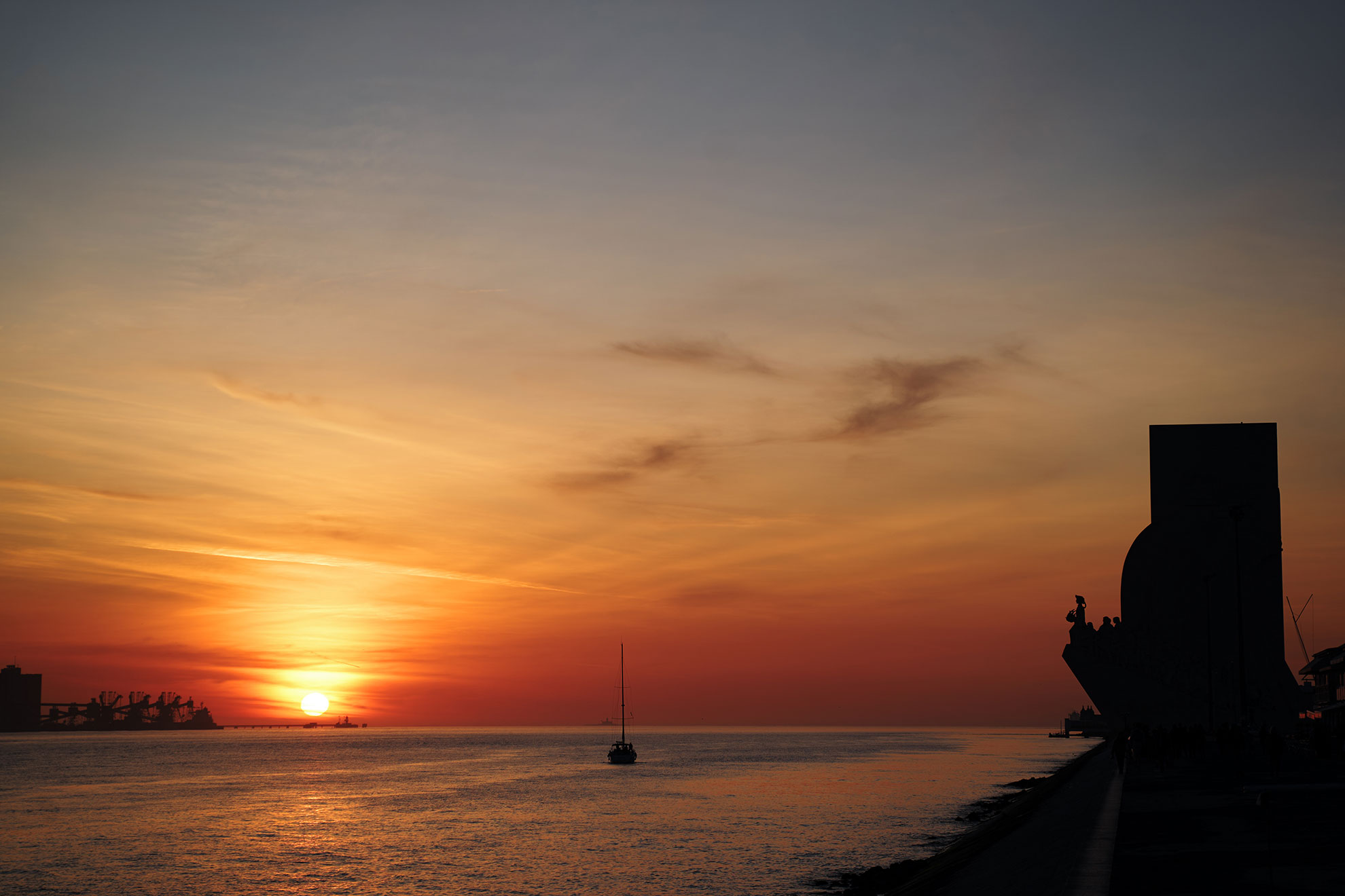 Golden sunset over the Tagus river in Lisbon with the 25 de Abril bridge and city skyline silhouetted against the sky
