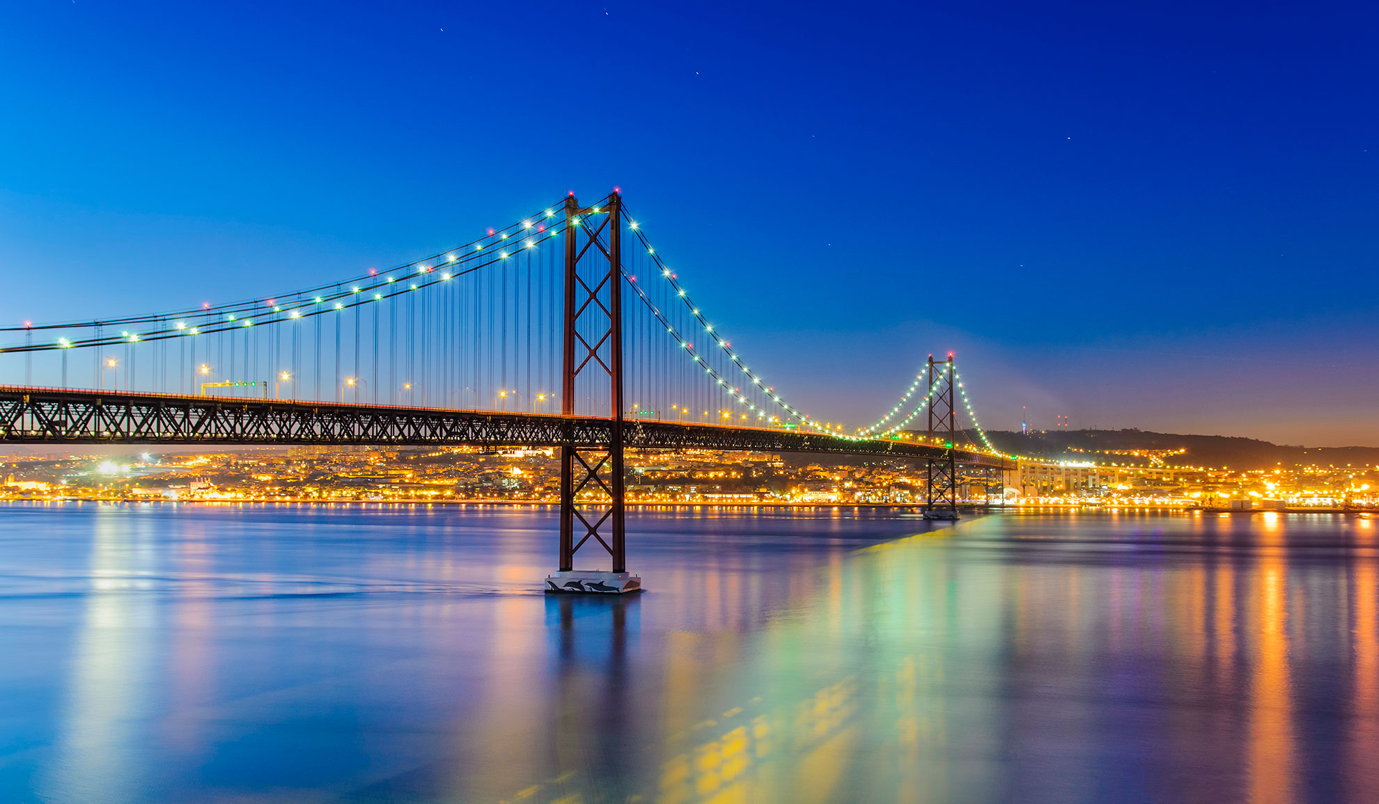 Lisbon illuminated at night with lights reflected on the calm waters of the Tagus river