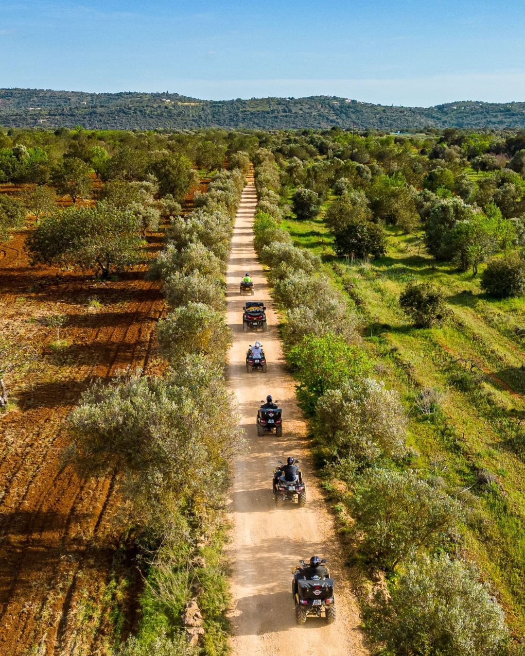 ATV quad bike on a dusty off-road trail through the Algarve countryside with golden hills in the background