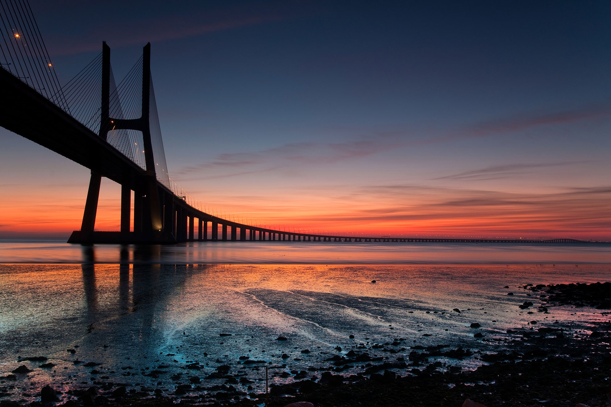 Sailboats and traditional vessels on the Tagus River with Lisbon's waterfront in the background