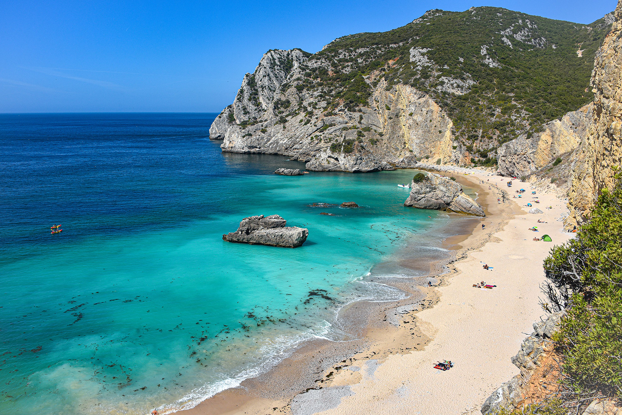 Turquoise waters below the limestone cliffs of Arrábida Natural Park, Setúbal