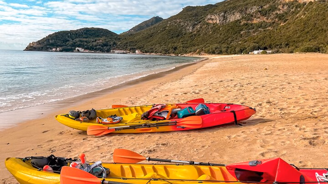 Kayakers paddling through a sea cave in Arrábida Natural Park
