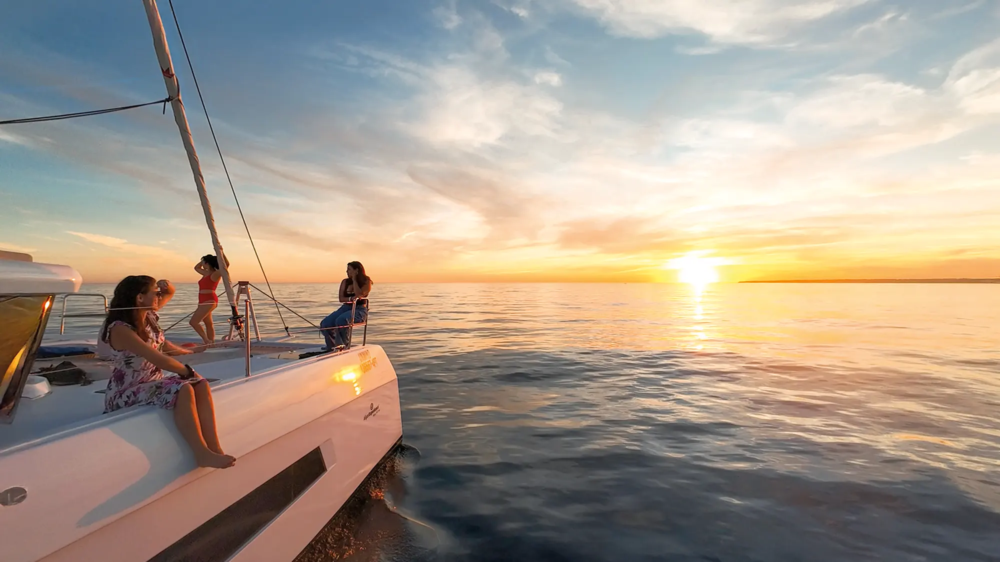 Catamaran on the Algarve sea at sunset with orange-lit limestone cliffs in the background