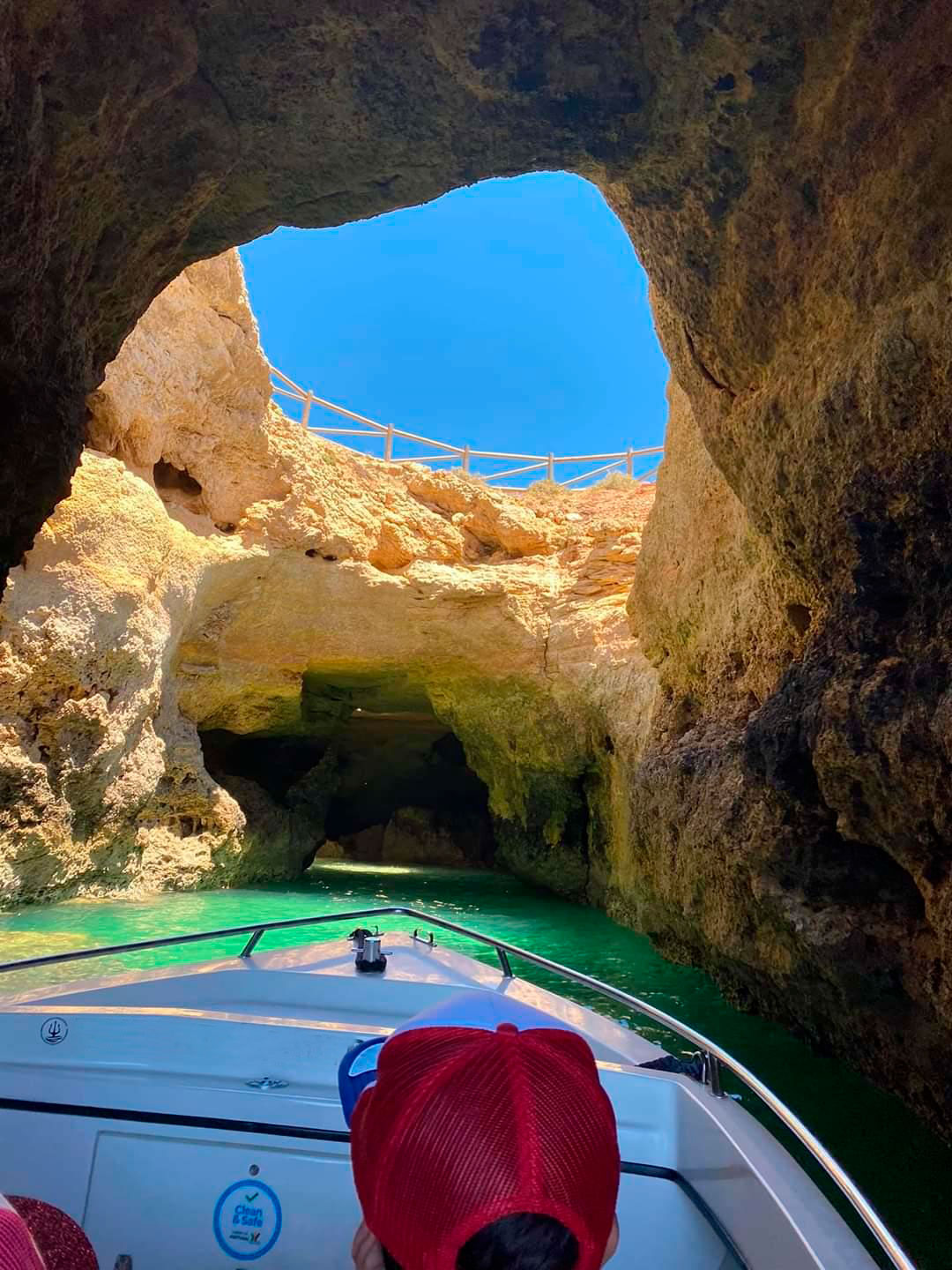 Small boat entering a sea cave in the Algarve limestone cliffs, interior lit by a natural skylight