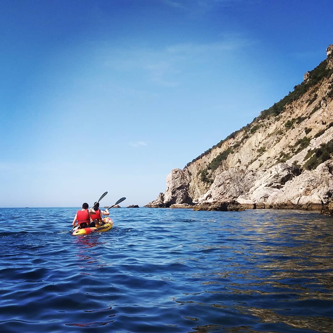 Kayakers navigating limestone sea caves along the Arrábida coastline near Sesimbra