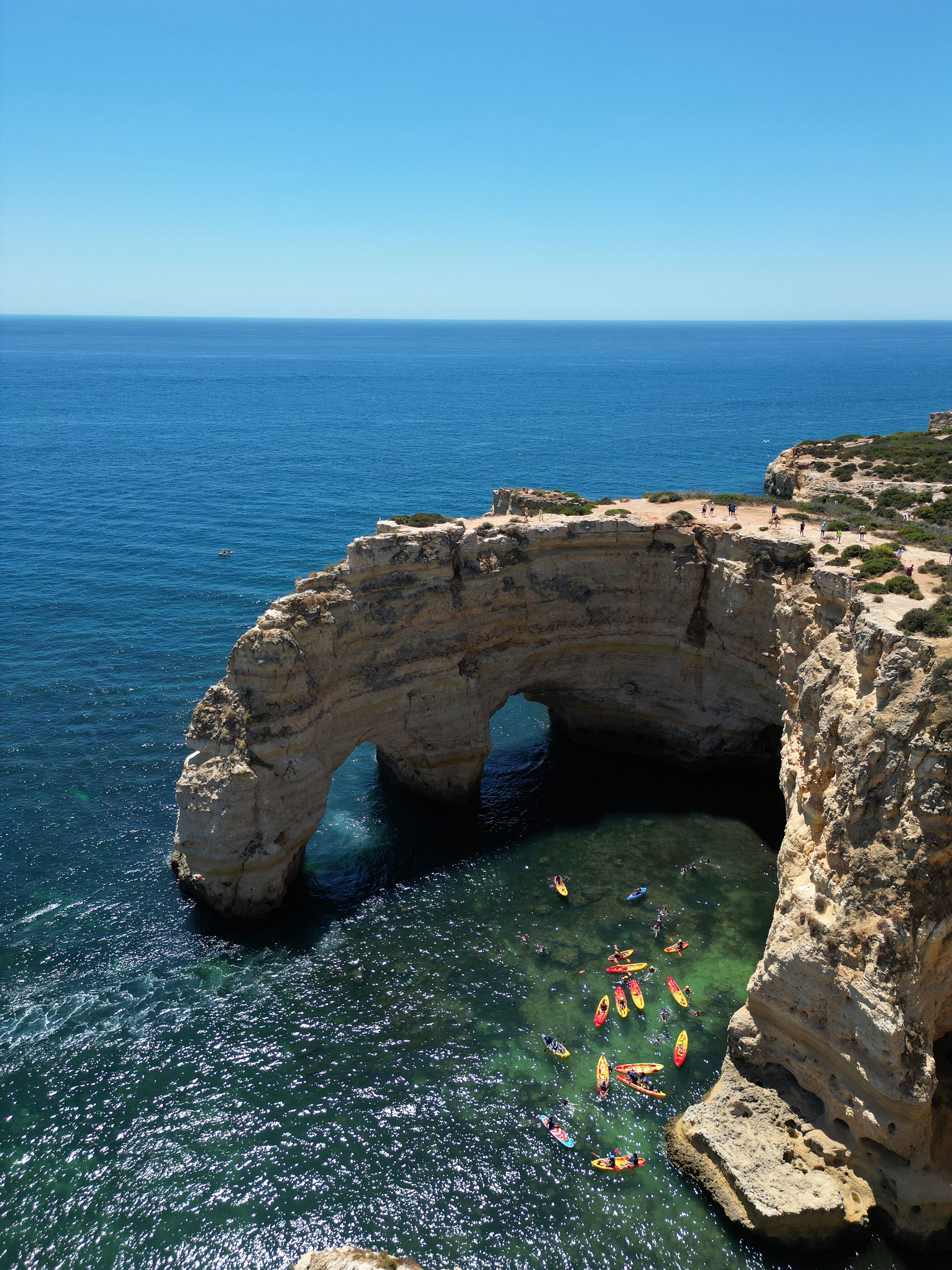 Kayak paddling along the golden limestone cliffs of the Algarve coast near Benagil