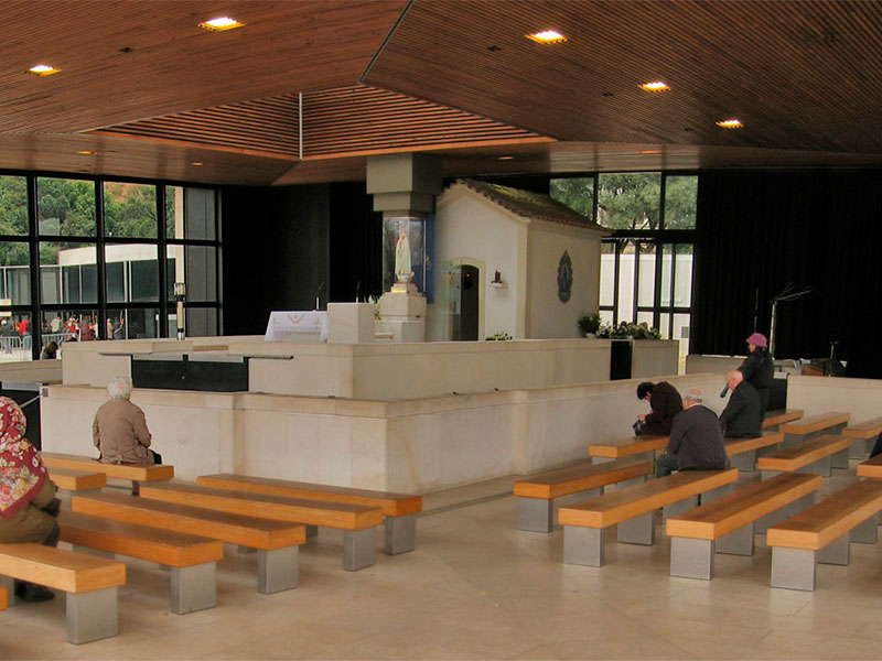 The Chapel of the Apparitions at dusk, with candles burning on the iron grill outside