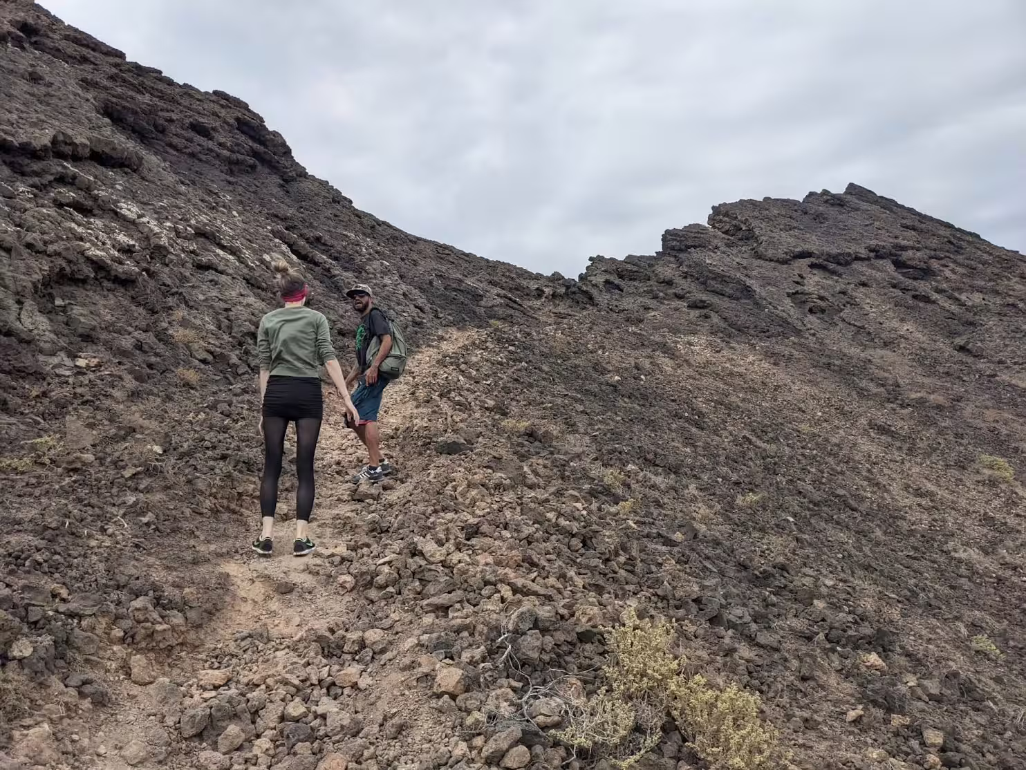 A guided hiking group on the crater rim of Volcano Viana on São Vicente island in Cape Verde, with the dramatic lunar volcanic landscape and the city of Mindelo visible below