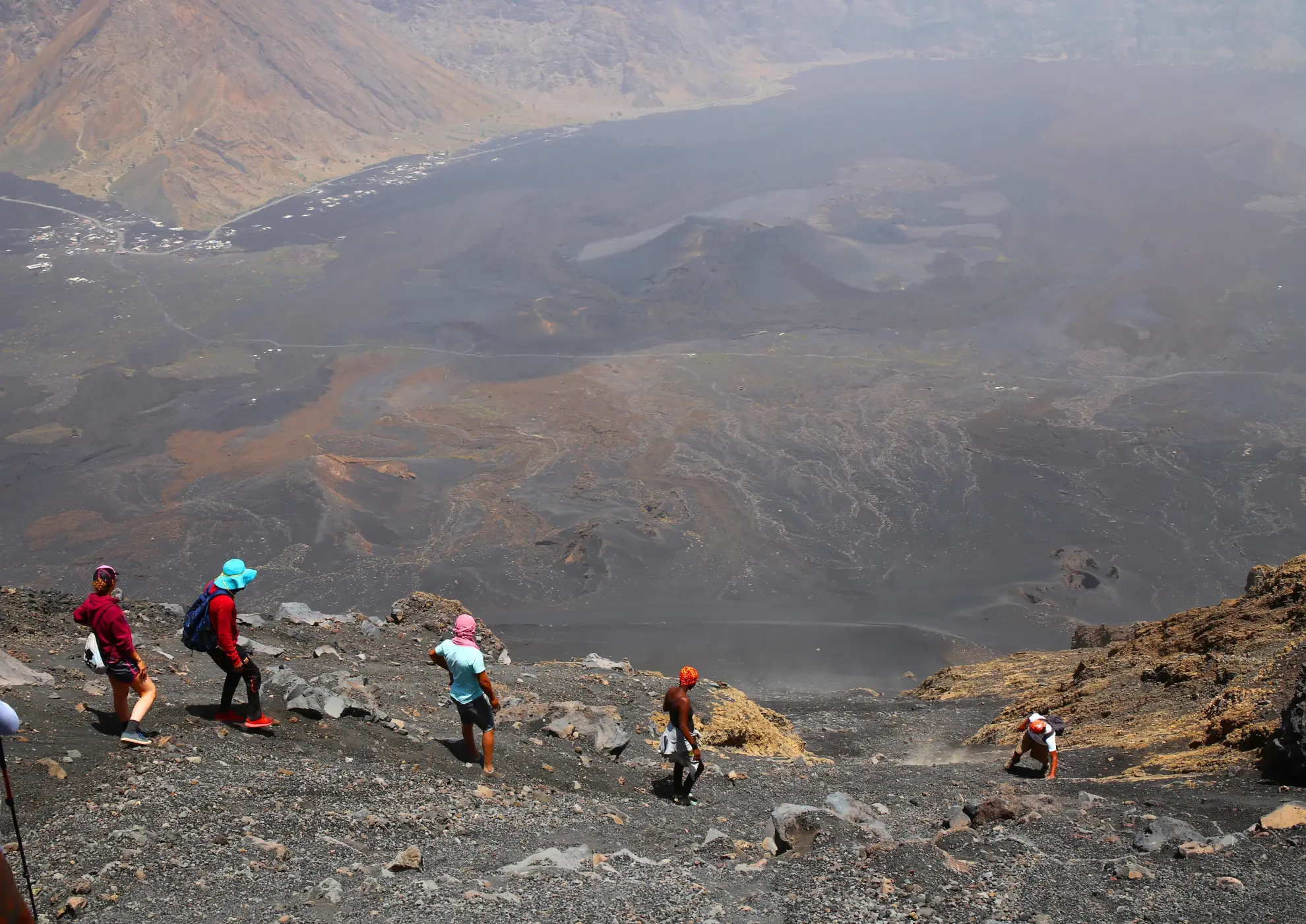 Group of hikers at the summit of Pico do Fogo volcano on Fogo Island, Cape Verde, with a panoramic view above the clouds stretching across the Atlantic