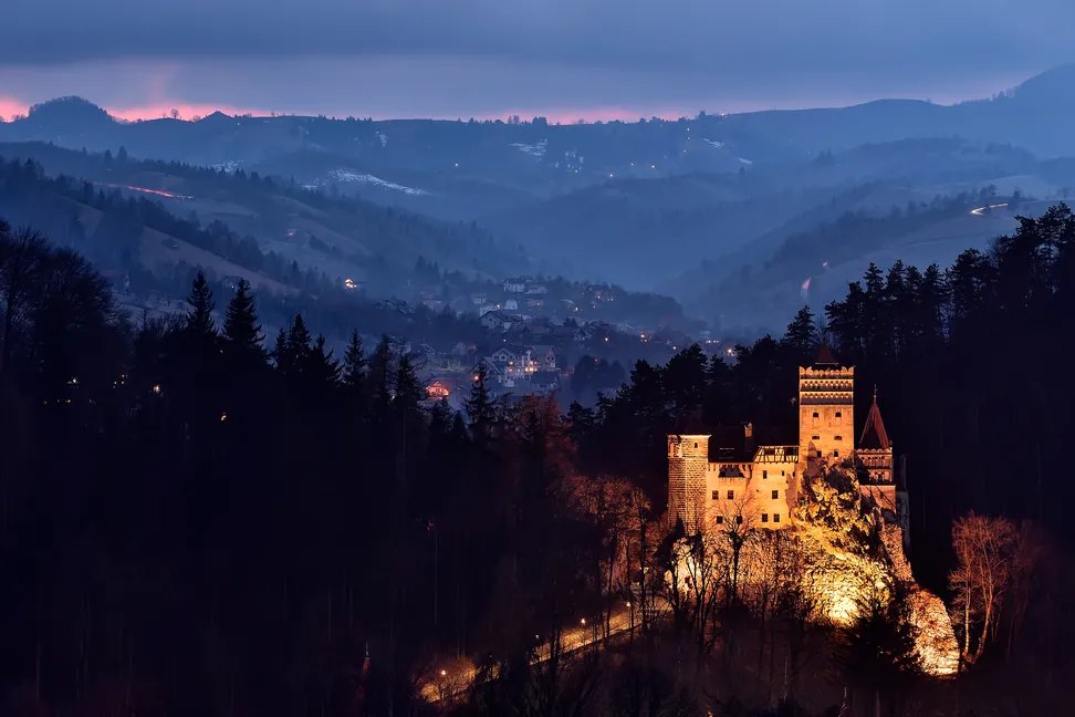 El Castillo de Bran iluminado al atardecer en su valle, con las colinas al fondo