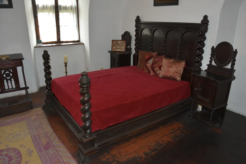 Una cama de madera tallada en una habitación del Castillo de Bran