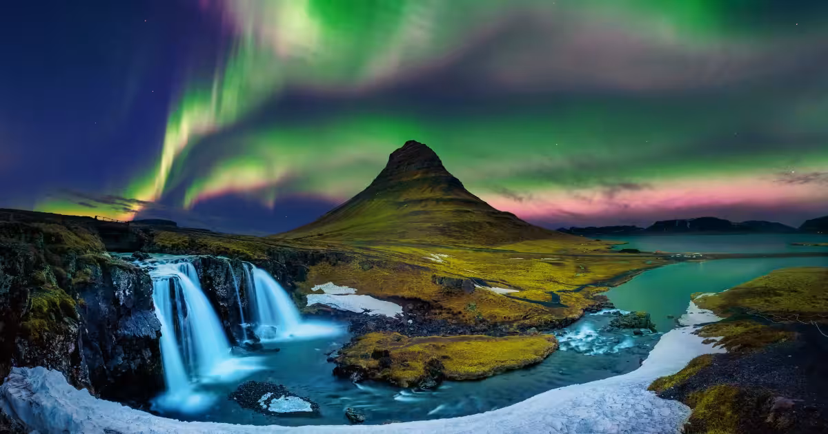 Aurora boreale che danza su un paesaggio islandese innevato di notte.