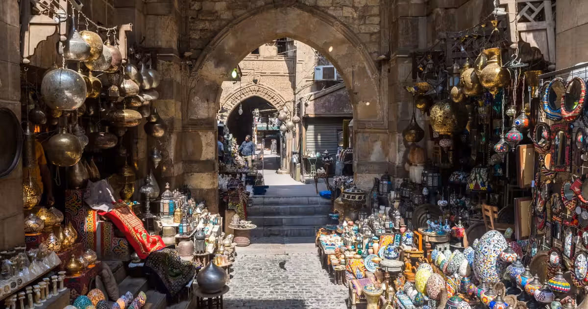 Vivace bazar di Khan el Khalili al tramonto con arcate illuminate da lanterne e venditori.