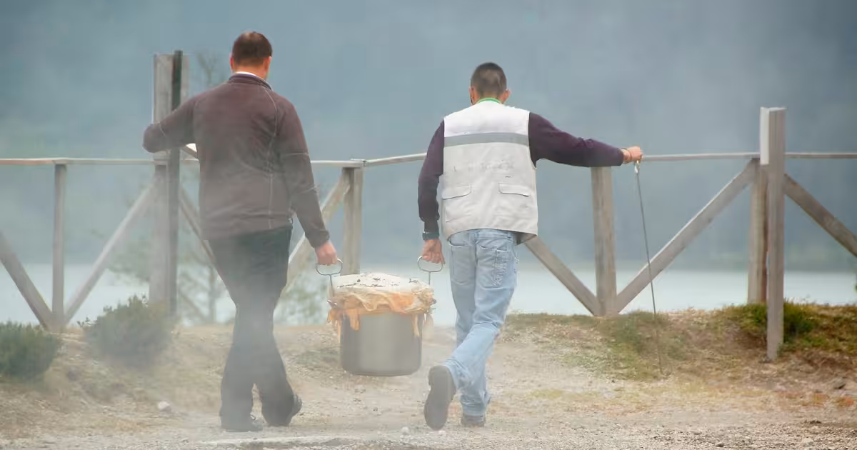 Chef lifting a steaming clay pot from volcanic soil at Furnas Lake, S&atilde;o Miguel.