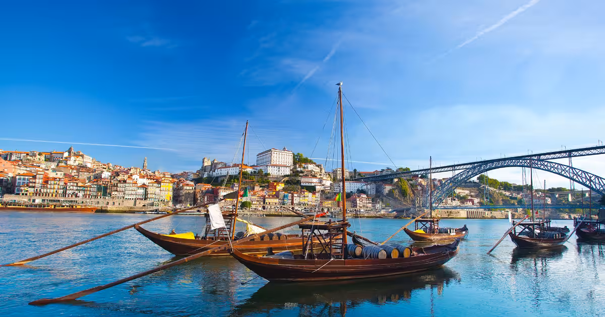 Traditional Rabelo boats moored on the Douro River with Porto's Ribeira waterfront behind.