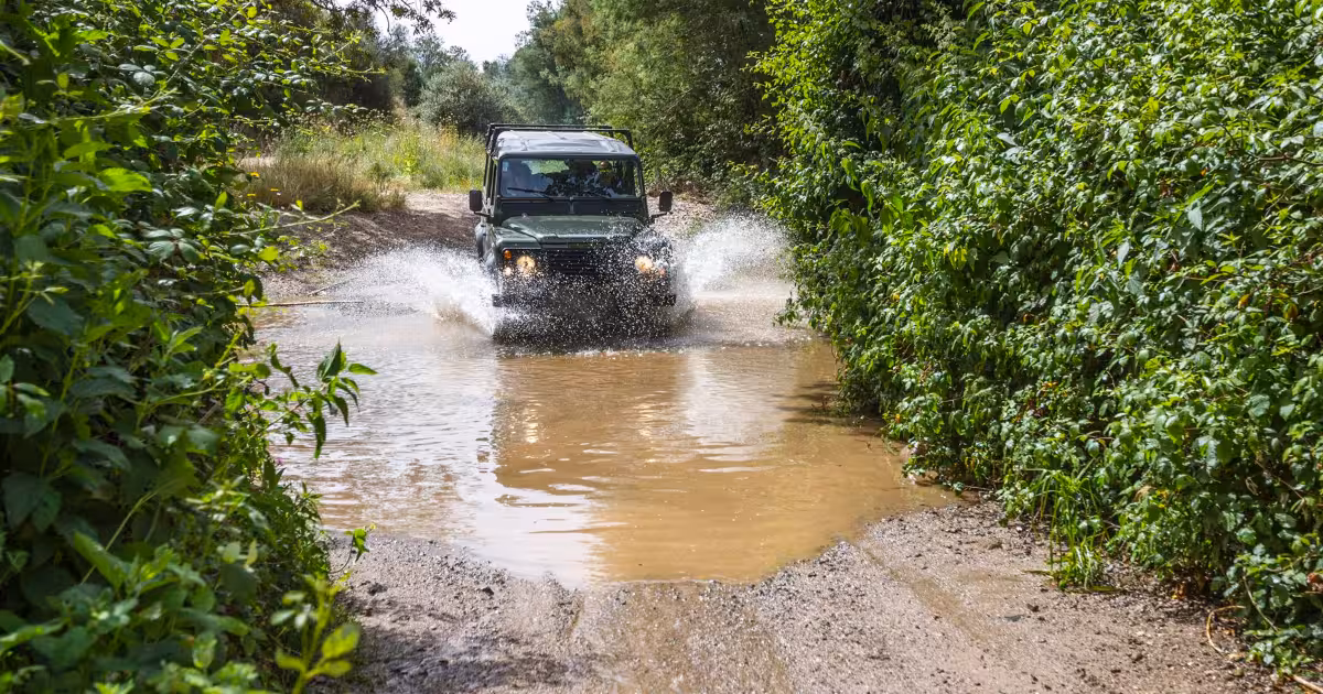 Red 4x4 jeep kicking up dust on a mountain trail in the Algarve hinterland.